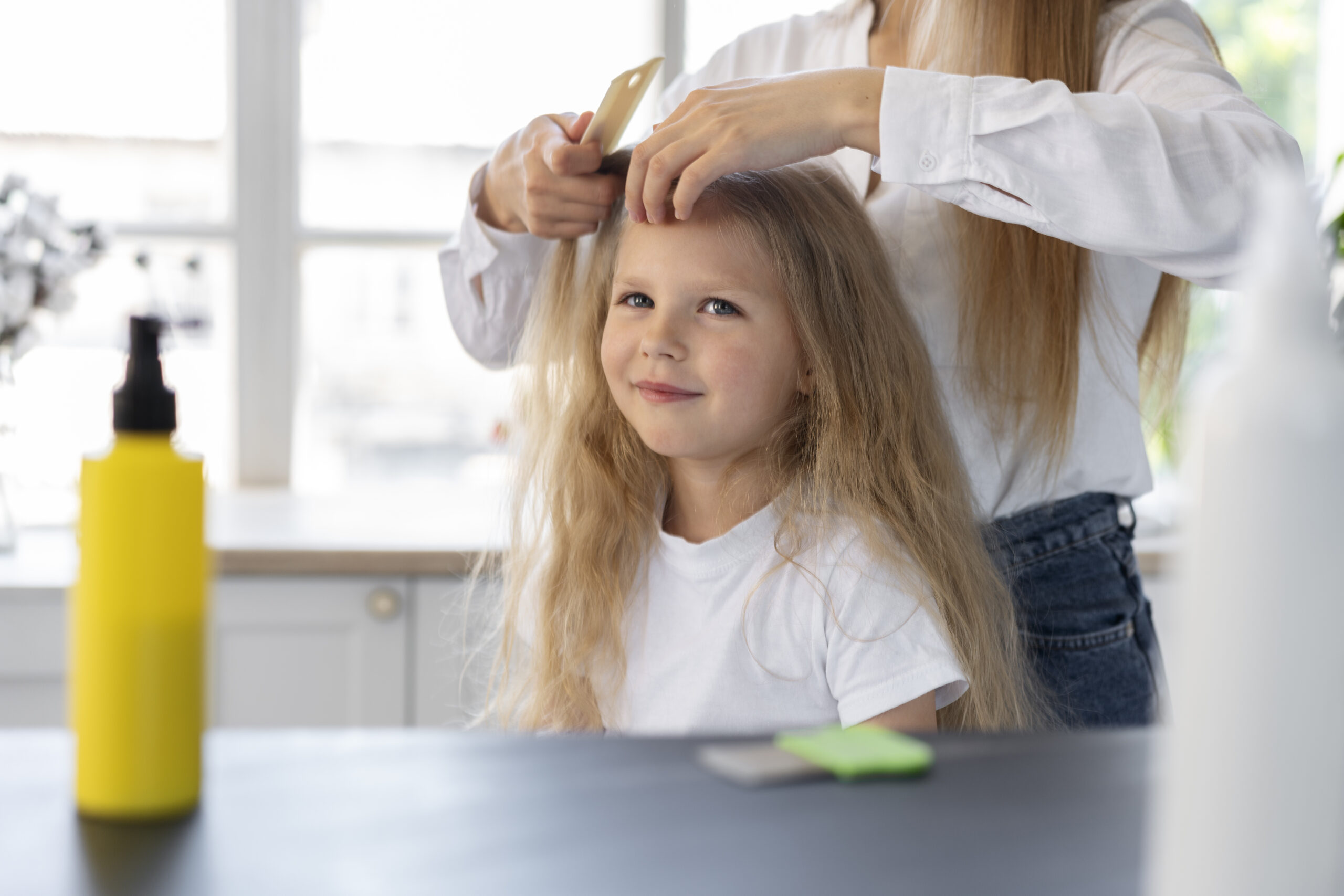 woman combing a young girls hair for head lice